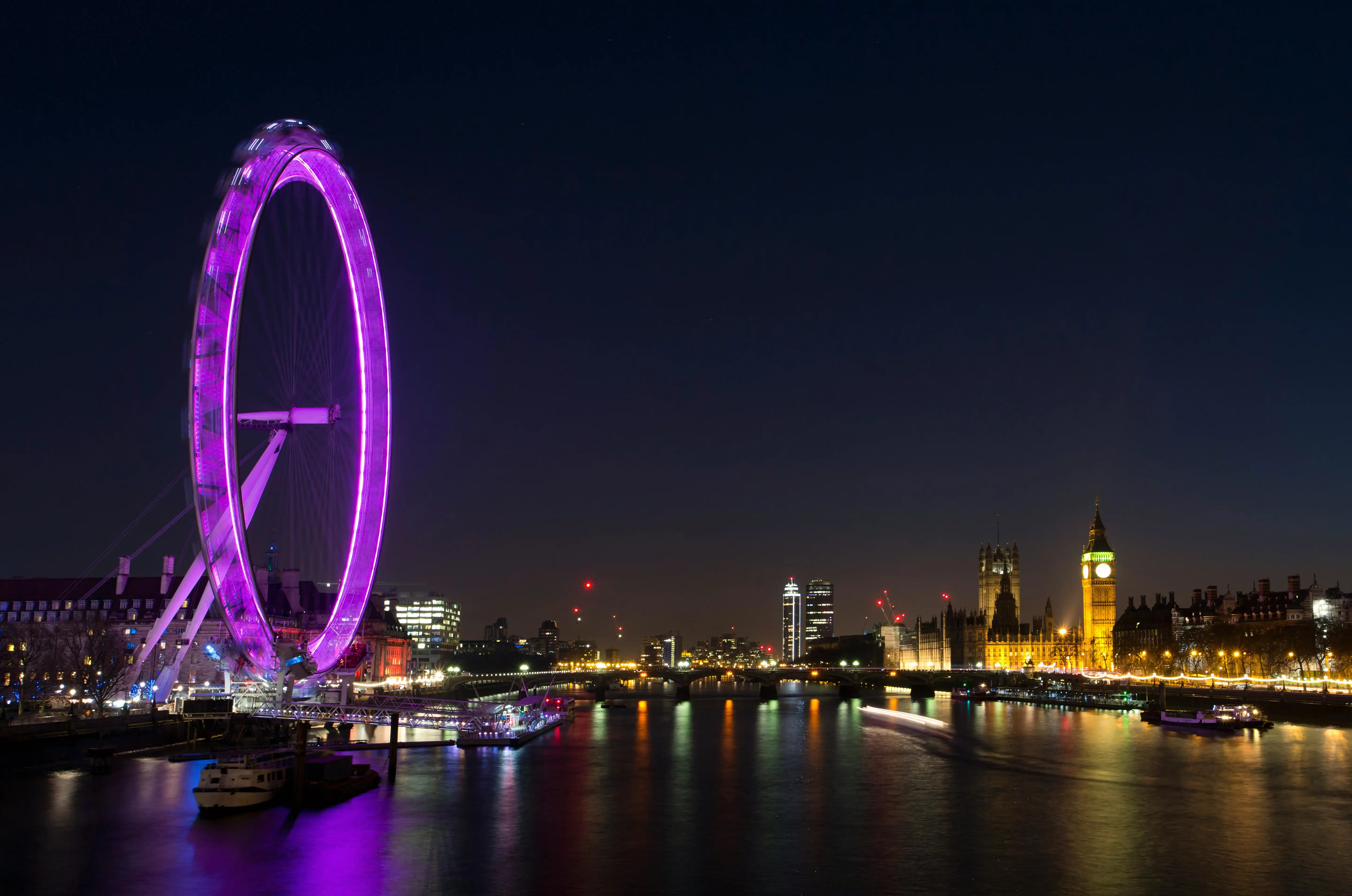London cityscape at night with illuminated buildings and river reflections